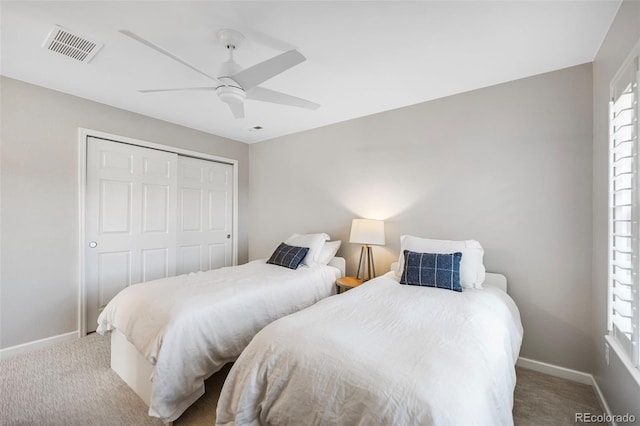 bedroom with a closet, light colored carpet, visible vents, multiple windows, and baseboards