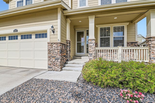 14067 Hudson St, Thornton, CO 80602 - view of exterior entry with a garage, stone siding, a porch, and driveway