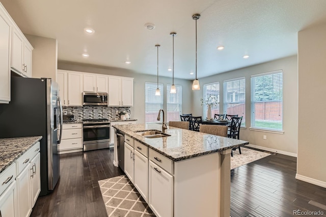 14067 Hudson St, Thornton, CO 80602 - kitchen featuring stainless steel appliances, a sink, dark wood-style floors, tasteful backsplash, and white cabinetry