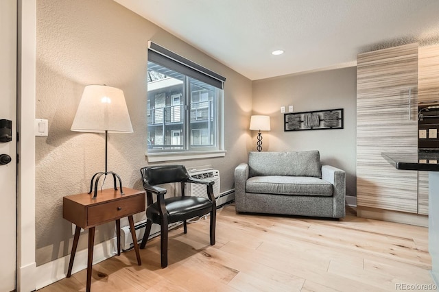 sitting room with light hardwood / wood-style flooring and a baseboard heating unit