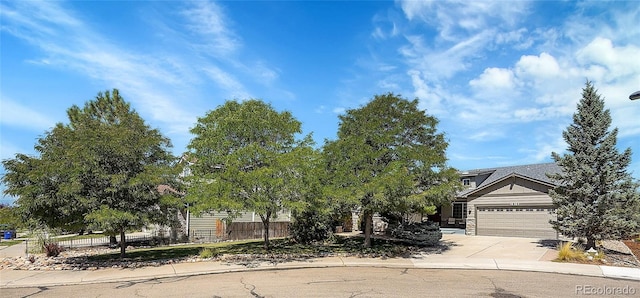 obstructed view of property featuring an attached garage, fence, and concrete driveway