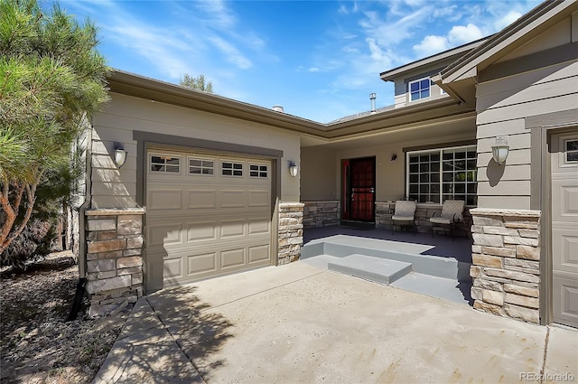 view of front of property with stone siding, a porch, an attached garage, and driveway