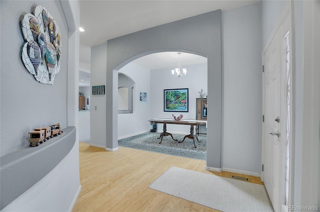 interior space with baseboards, arched walkways, and wood finished floors