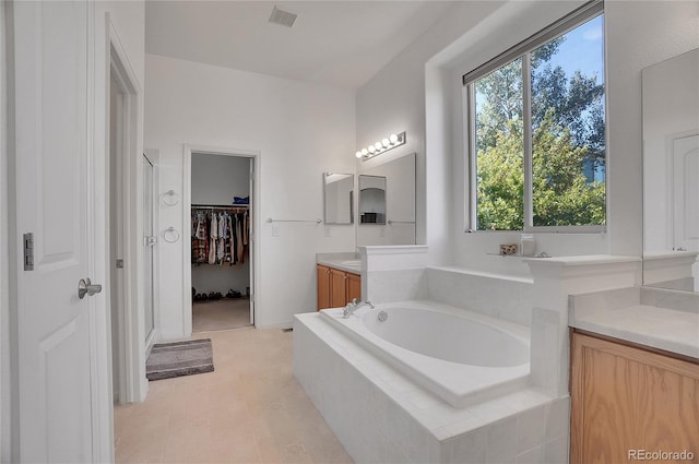 bathroom featuring a walk in closet, visible vents, vanity, a shower stall, and a bath