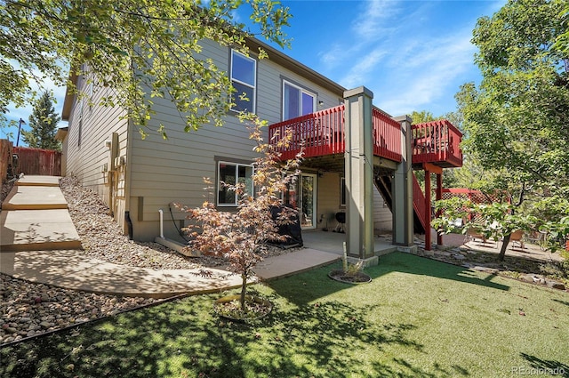 back of property with stairway, fence, a deck, a yard, and a patio area