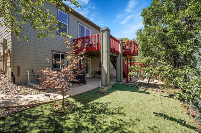 rear view of house featuring a wooden deck, a lawn, and a patio area