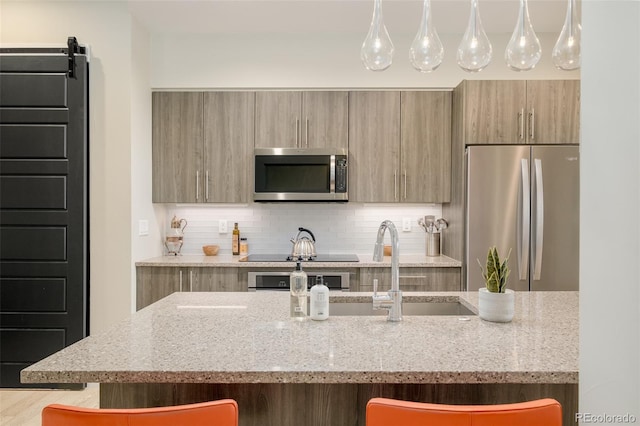 kitchen featuring a barn door, appliances with stainless steel finishes, a breakfast bar, and light stone counters