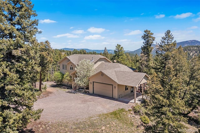 6252 King Dr, Evergreen, CO 80439 - view of front of house featuring dirt driveway, an attached garage, a mountain view, and a shingled roof