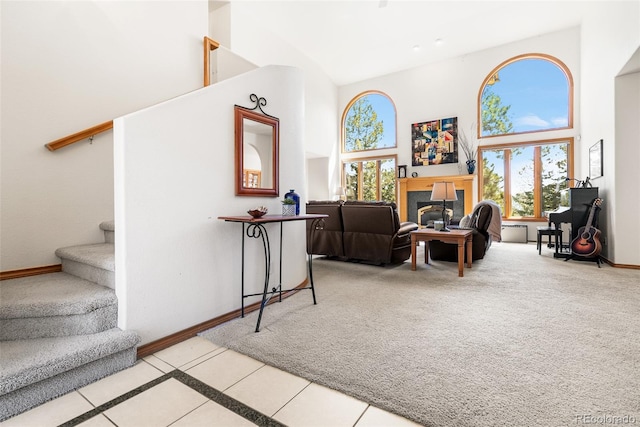 6252 King Dr, Evergreen, CO 80439 - tiled living area featuring a high ceiling, stairway, baseboards, a glass covered fireplace, and carpet floors