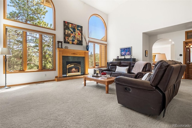 6252 King Dr, Evergreen, CO 80439 - carpeted living area with arched walkways, high vaulted ceiling, a warm lit fireplace, and baseboards
