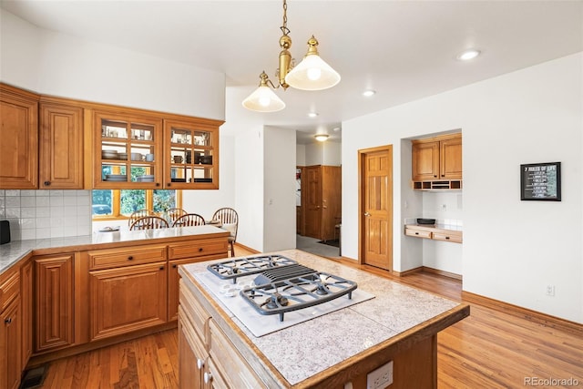 6252 King Dr, Evergreen, CO 80439 - kitchen featuring white gas cooktop, light countertops, brown cabinetry, light wood finished floors, and decorative backsplash