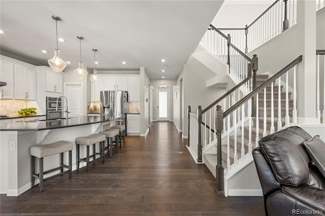 kitchen featuring sink, a breakfast bar area, white cabinetry, hanging light fixtures, and dark hardwood / wood-style floors