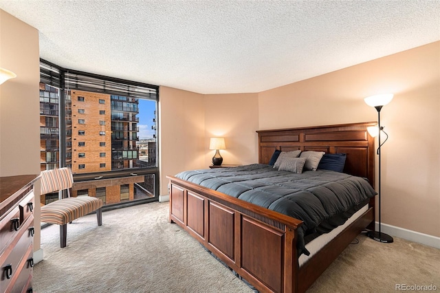 bedroom featuring light colored carpet, a textured ceiling, and a wall of windows