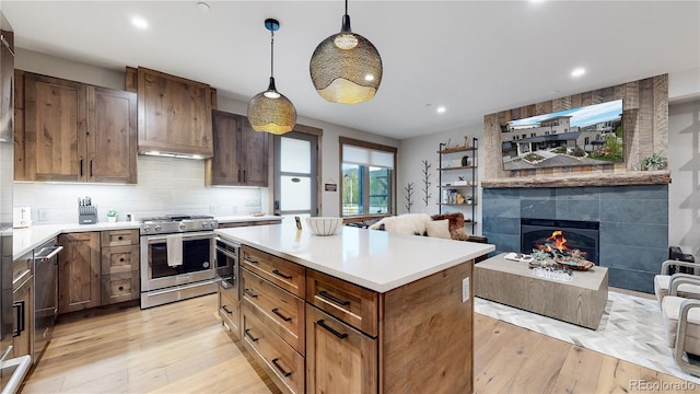 kitchen with pendant lighting, light hardwood / wood-style floors, a fireplace, and stainless steel stove