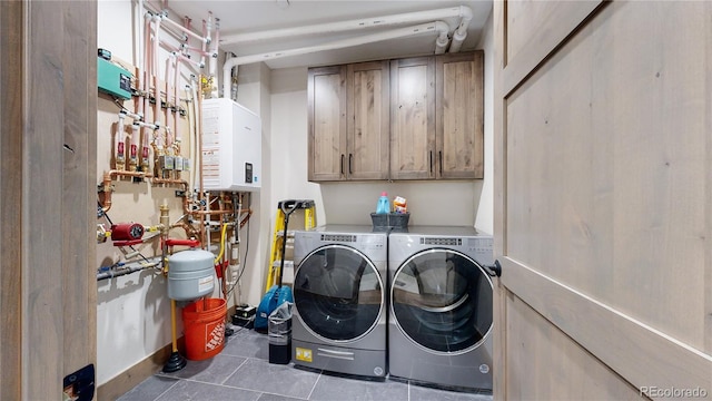 clothes washing area featuring cabinets, a workshop area, water heater, tile patterned flooring, and washer and dryer