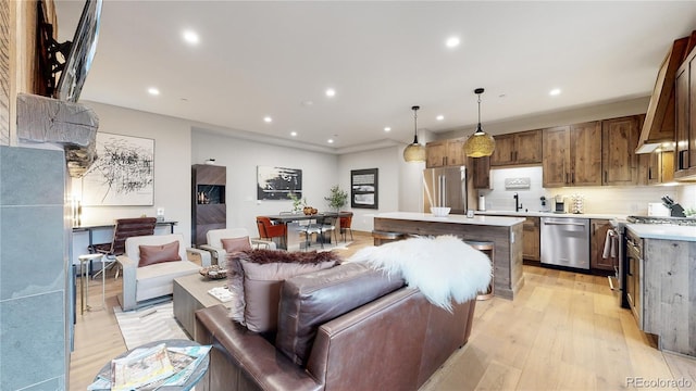 kitchen featuring pendant lighting, a center island, backsplash, light hardwood / wood-style floors, and stainless steel appliances