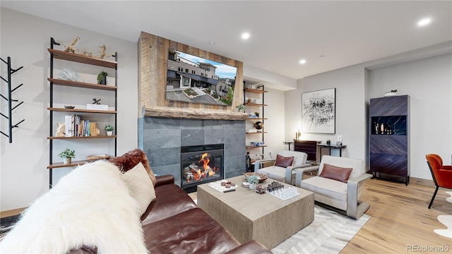 living room with a tiled fireplace and light hardwood / wood-style flooring