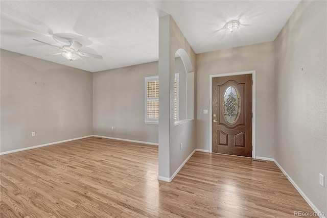 foyer entrance with baseboards, plenty of natural light, ceiling fan, and light wood finished floors