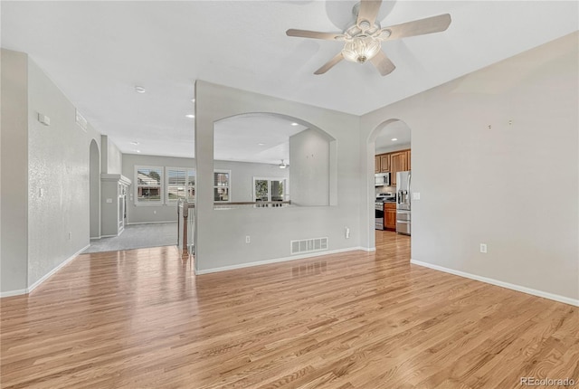 unfurnished living room with light wood-style flooring, baseboards, visible vents, and ceiling fan