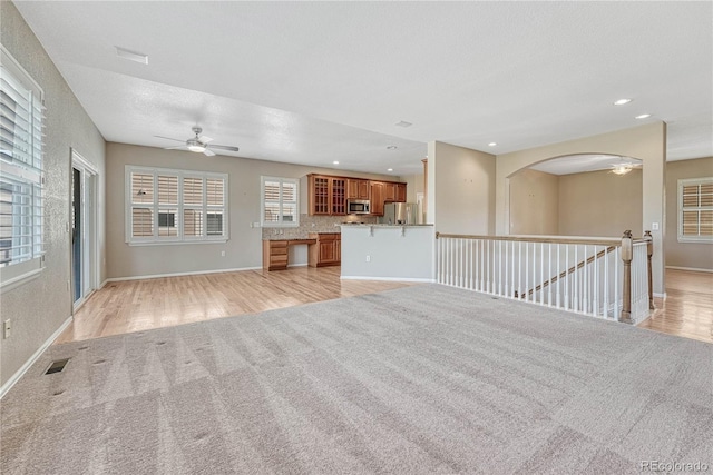 unfurnished living room featuring visible vents, baseboards, light wood-style floors, and ceiling fan