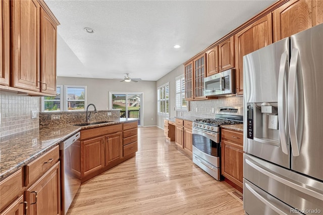 kitchen with a sink, light wood-style flooring, brown cabinetry, and stainless steel appliances