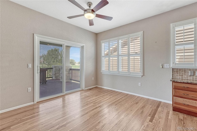 unfurnished room with light wood-style flooring, baseboards, a ceiling fan, and a textured wall