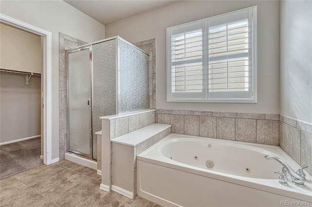 bathroom featuring a tub with jets, a stall shower, and a walk in closet