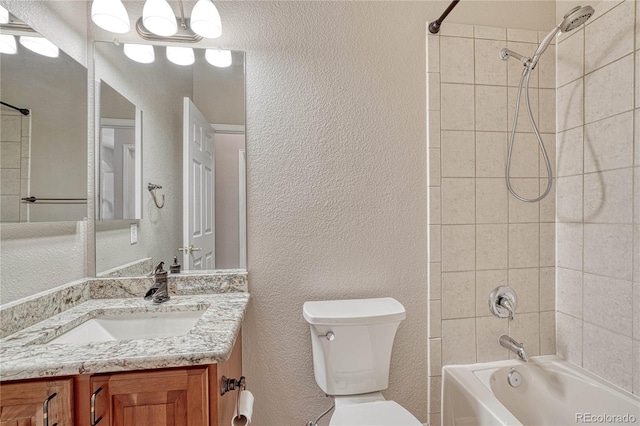 full bathroom with tub / shower combination, toilet, vanity, and a textured wall