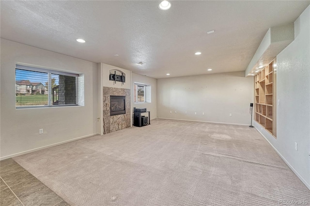 unfurnished living room featuring a glass covered fireplace, light carpet, recessed lighting, and a textured ceiling