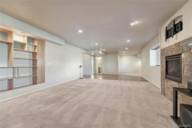 unfurnished living room with a glass covered fireplace, recessed lighting, a textured ceiling, and carpet