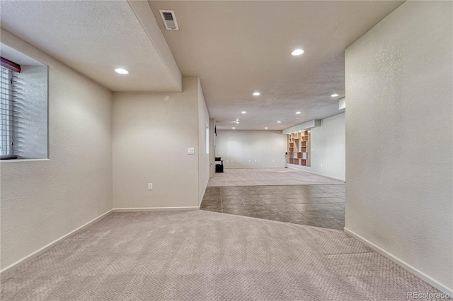 carpeted spare room with visible vents, recessed lighting, baseboards, and a textured wall