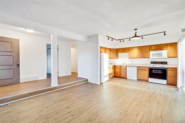 kitchen with a textured ceiling, light wood-type flooring, white appliances, and sink