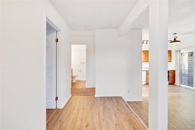 hallway with light hardwood / wood-style floors and a textured ceiling