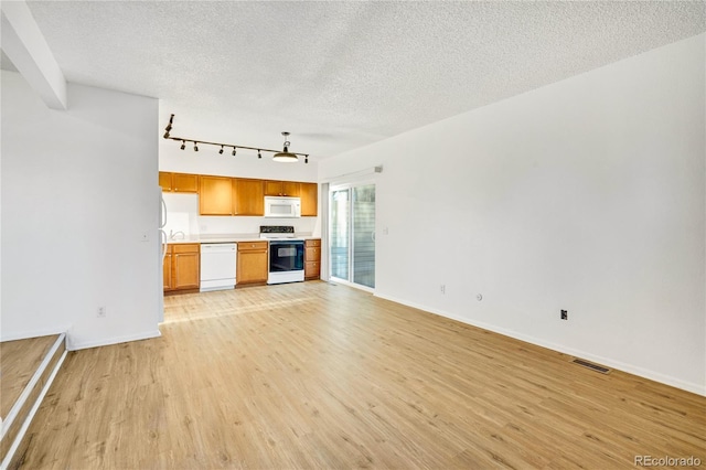 kitchen featuring a textured ceiling, rail lighting, white appliances, and light wood-type flooring