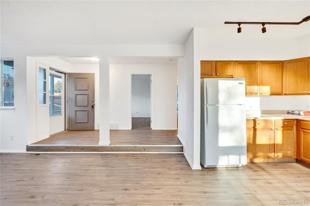 kitchen featuring a textured ceiling, light wood-type flooring, white fridge, and track lighting