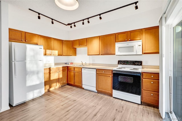 kitchen featuring white appliances, track lighting, sink, light hardwood / wood-style flooring, and a textured ceiling