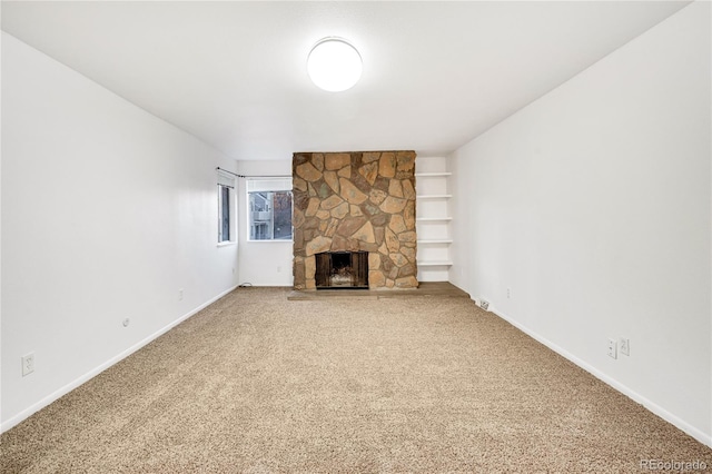 unfurnished living room featuring a stone fireplace and carpet floors