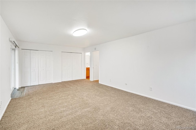 unfurnished bedroom featuring carpet and multiple closets