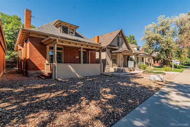 873 S Logan St, Denver, CO 80209 - view of front of house featuring a chimney, brick siding, covered porch, and a shingled roof