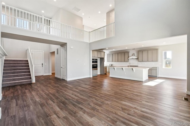 unfurnished living room with dark hardwood / wood-style flooring, a high ceiling, and sink