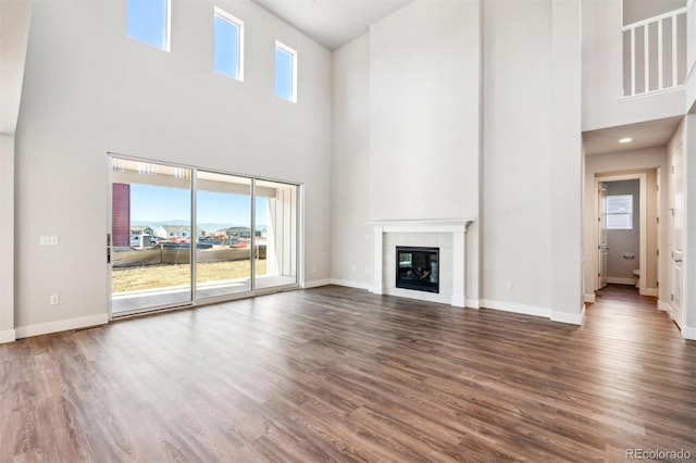 unfurnished living room featuring a fireplace, hardwood / wood-style floors, and a high ceiling