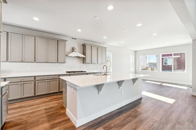 kitchen featuring a center island with sink, stainless steel gas cooktop, dark wood-type flooring, and sink