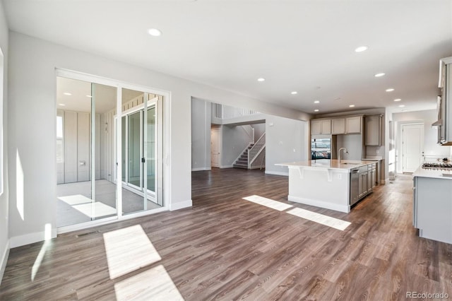 kitchen with stainless steel gas stovetop, a center island with sink, dark hardwood / wood-style floors, and sink