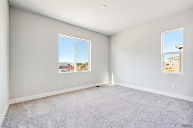 carpeted spare room featuring a healthy amount of sunlight