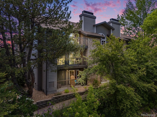 2575 S Syracuse Way Unit K201, Denver, CO 80231 - back of house at dusk featuring a balcony and a chimney