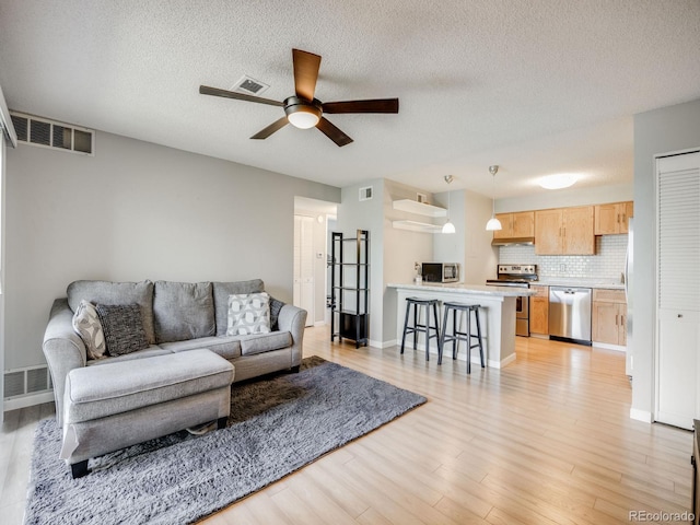 2575 S Syracuse Way Unit K201, Denver, CO 80231 - living room with ceiling fan, light wood-type flooring, a textured ceiling, and baseboards