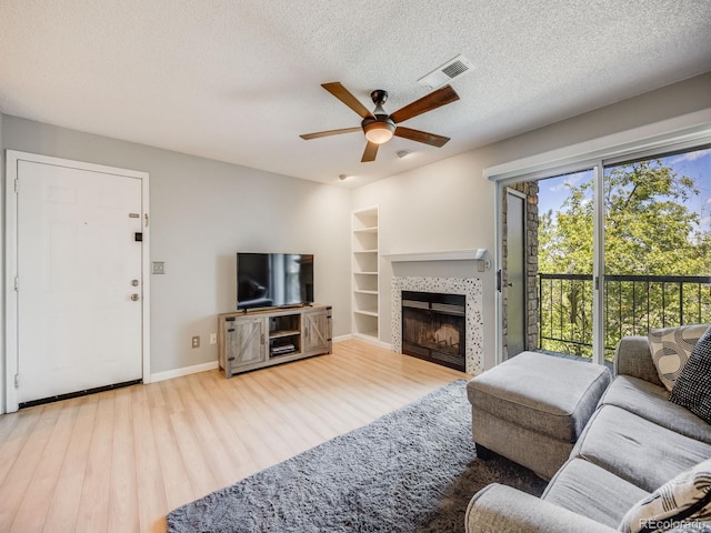 2575 S Syracuse Way Unit K201, Denver, CO 80231 - living area featuring a ceiling fan, wood finished floors, built in shelves, a fireplace, and a textured ceiling