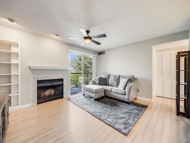 2575 S Syracuse Way Unit K201, Denver, CO 80231 - living area with a ceiling fan, light wood finished floors, a textured ceiling, a tile fireplace, and built in shelves