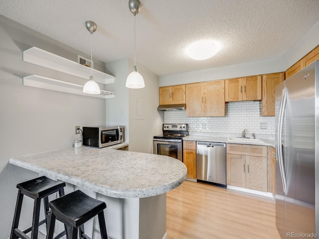 2575 S Syracuse Way Unit K201, Denver, CO 80231 - kitchen with stainless steel appliances, a sink, a peninsula, light wood finished floors, and light countertops