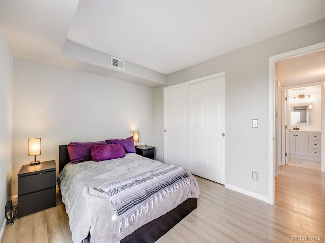 2575 S Syracuse Way Unit K201, Denver, CO 80231 - bedroom with baseboards, light wood finished floors, a closet, and a sink